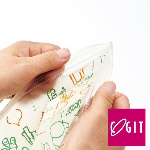 雙手正在打開一個透明的環保保鮮袋，袋子內印有綠色和橘色的蔬菜水果圖案，例如胡蘿蔔、豌豆莢和鍋子。