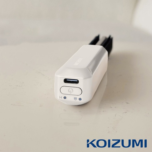 白色圓潤的迷你美髮造型器，帶有USB充電孔和電源按鈕，頂部印有KOIZUMI品牌標誌。