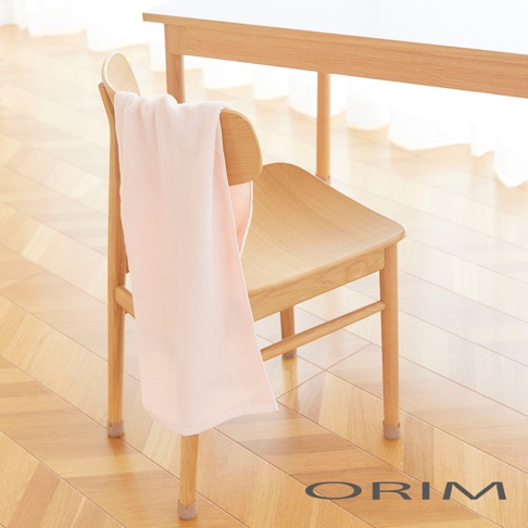 一條淺粉色、柔軟的迷你毛巾，搭在一張木質椅子上，背景是明亮的居家環境。