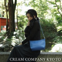 藍色皮革手提側背包，簡約方形設計，配有細長可調式肩帶，適合日常攜帶。