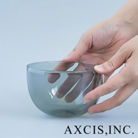 一隻手捧著一個淺灰色、圓潤的玻璃點心碗，碗的邊緣有細微的反光。