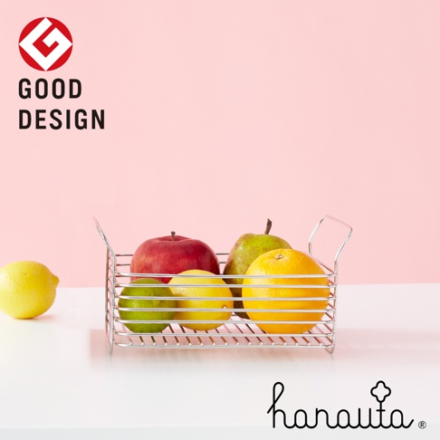 不鏽鋼淺型收納籃，盛裝著紅蘋果、綠梨、綠萊姆、黃檸檬和橘子，籃子為銀色金屬線條編織而成，有兩個提把。