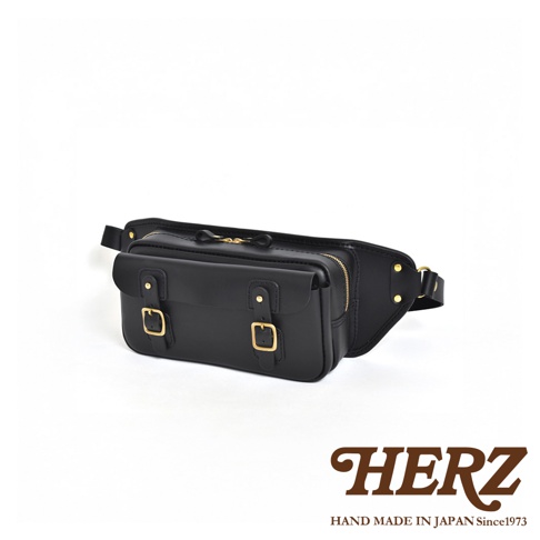 黑色皮革騎士隨身斜背包，設有兩個可調節扣帶的翻蓋前袋，金色拉鍊和五金件，皮帶可調節。