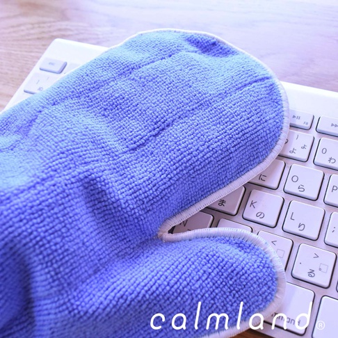 一隻藍色超細纖維除塵清潔手套，放置於白色鍵盤上，手套表面紋理清晰，邊緣有白色滾邊。