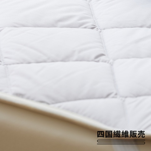 雙人加大尺寸的白色羊毛床墊，表面有菱形格紋縫線，質感柔軟蓬鬆，邊緣為米白色滾邊。