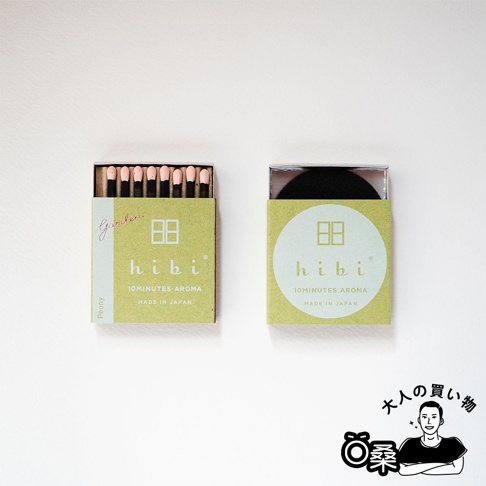 香氛火柴禮盒，綠色紙盒包裝，左盒內含一疊粉色火柴頭的火柴，標示「Garden. Peony hibi 10MINUTES AROMA MADE IN JAPAN」；右盒內含黑色圓盤，標示「hibi 10MINUTES AROMA MADE IN JAPAN」。