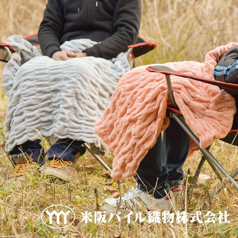 兩條室內外兩用波浪細絨抗摩四季毯，一條為淺灰色，另一條為珊瑚橘色，皆覆蓋於戶外折疊椅上，展示其細緻的織紋與柔軟的質感。