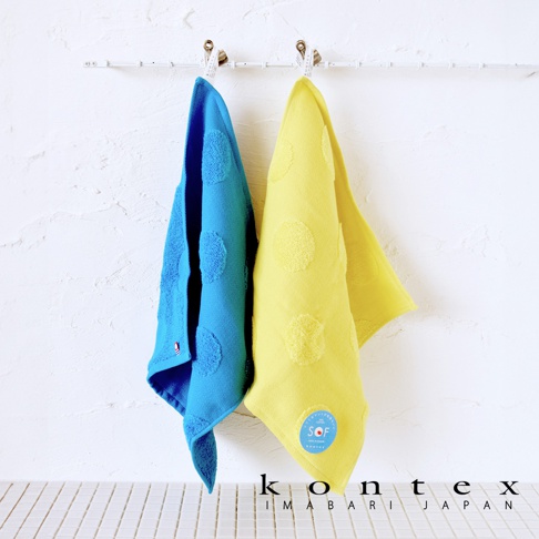 兩條今治水玉點點無撚紗質柔膚方巾，一條為藍色，一條為黃色，皆掛在白牆上的掛鉤上，有著明顯的點點紋路。