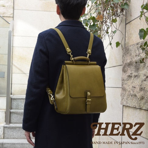 職人手作皮革屋瓦風後背包 R-15，橄欖綠，採用皮革材質，造型簡約，配有金屬扣環和可調整背帶。