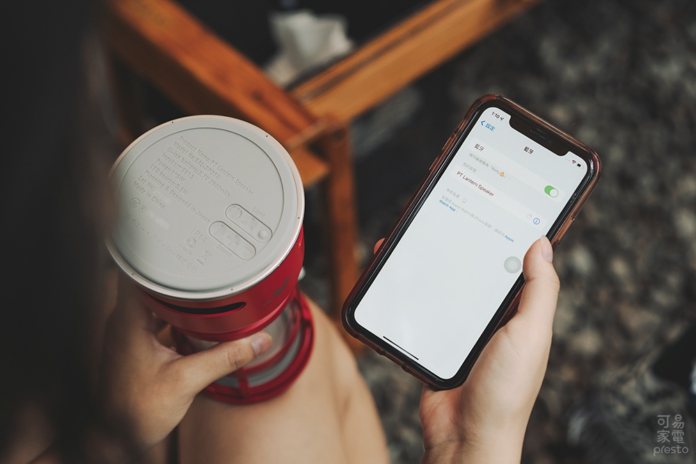 一名使用者手持紅色神燈造型音響，旁邊有另一隻手拿著 iPhone，螢幕顯示藍牙連線至「PT Lantern Speaker」。