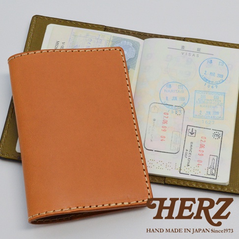 職人手作皮革經典護照套，淺棕色皮革外觀，縫線精緻，內頁展示有日本、西班牙等國家的出入境章。