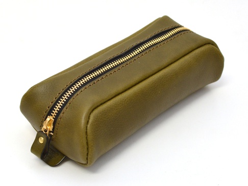 橄欖綠皮革製成的圓角收納筆袋，配有金色拉鍊和一個小的皮革拉環。