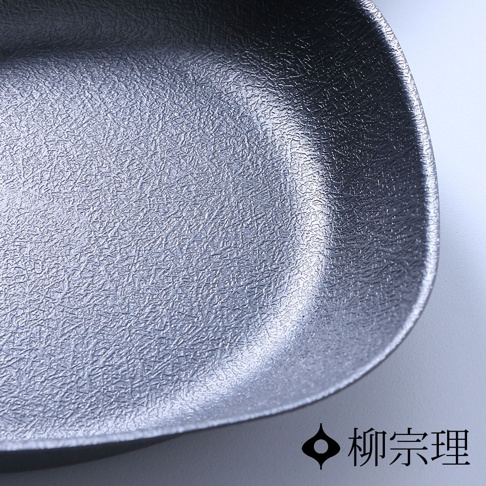 特寫拍攝柳宗理雙網紋單手鐵鍋的內部鍋底，呈現出獨特的粗糙網紋金屬質感，鍋緣線條圓潤流暢，右下角印有標誌性的柳宗理品牌名稱與圖示。