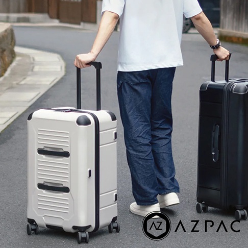 兩咖 AZPAC Trucker 旅行箱，一咖為米白色，另一咖為黑色，皆為 26 吋，外觀堅固，配有可伸縮拉桿與四個萬向輪，展現其防爆拉鍊與耐用材質的設計。