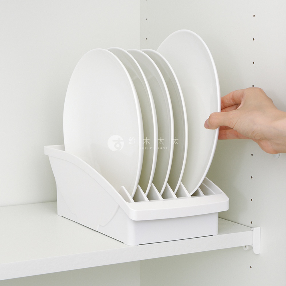 白色櫥櫃式餐盤收納架，架上整齊擺放著五個白色盤子，一隻手正要放入最右邊的盤子。