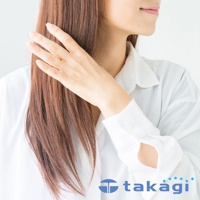 一名女子側臉，手輕觸一頭棕色長髮，身穿白色襯衫，露出部分頸部及手臂，白色襯衫袖口處可見品牌 Logo。