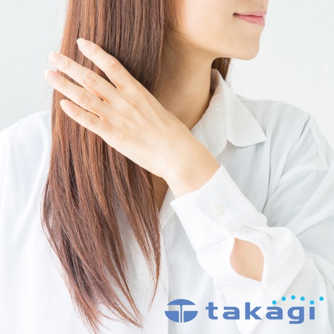 一名女子側臉，手輕觸一頭棕色長髮，身穿白色襯衫，露出部分頸部及手臂，白色襯衫袖口處可見品牌 Logo。