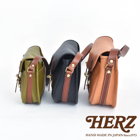 職人手作皮革傳統釣魚包，展示綠色、黑色和棕色三款。包款由皮革製成，搭配同色系或對比色皮革的背帶和裝飾，並帶有金屬扣環。