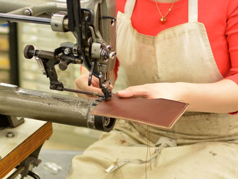 職人手作皮革存摺文件收納夾，使用咖啡色皮革，透過縫紉機進行車縫。