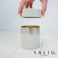 簡約錫製茶葉罐，米白色罐身搭配銀色飾帶，內蓋為金色，氣密防潮設計。