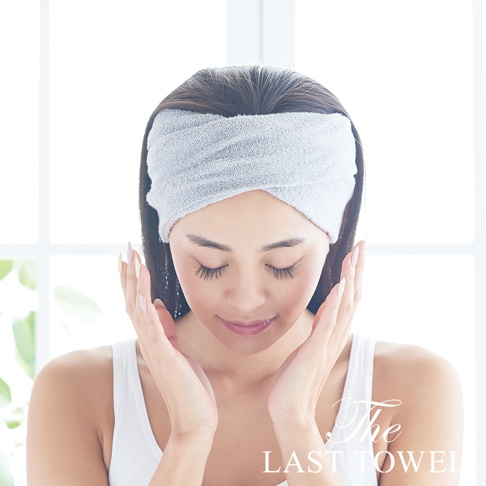 一位女性戴著灰色純棉吸水髮巾，頭髮向後梳，雙手輕觸臉頰。