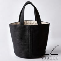 黑色三河木綿刺子織圓底水桶包，有兩個提把，包身呈現立體織紋，內裡為米白色。