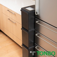 黑色三層抽屜式分類垃圾桶，具備銀色抽屜把手，與木紋櫥櫃和不銹鋼冰箱並列於廚房檯面下。