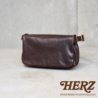 深棕色皮革製成的斜背包，側面可見金屬扣環，包身線條圓潤，展現職人手作質感。