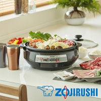 黑色鐵板萬用鍋 EP-PAF25，鍋內盛滿各式食材，包括肉片、蔬菜、丸子和豆腐。鍋旁有兩個金屬杯、一碗白飯、一碟醬料及一碟肉片。