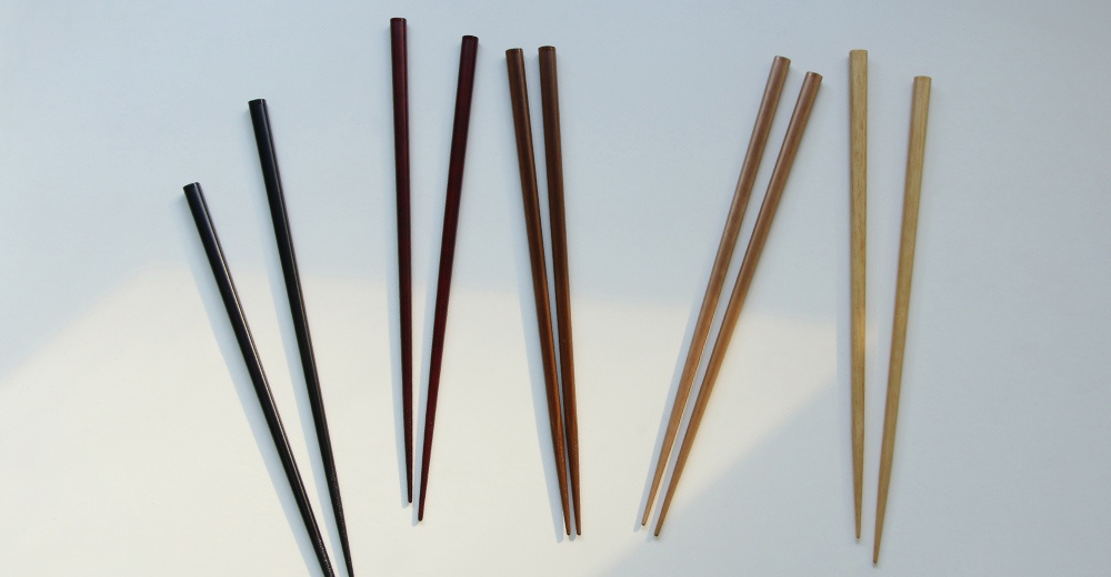 五色原木筷組合，包含黑色、深紅、紅棕、淺棕及原木色共五種顏色，每雙長度約22.5公分，皆為圓柱形，一端為方形，另一端為鈍圓形。