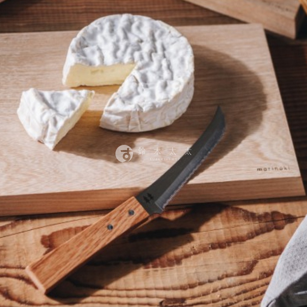 日式木柄起司刀放在榆木砧板上，砧板上有一塊被切開的圓形起司，旁邊有一小塊起司，砧板上有志津匠 morinoki 品牌標誌
