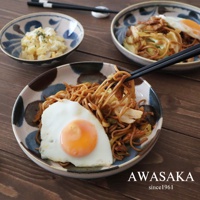 筆青釉繪料理盤，盤面帶有藍色、褐色、白色的圓形釉彩圖案，盛有炒麵與荷包蛋，盤中以筷子夾起麵條。