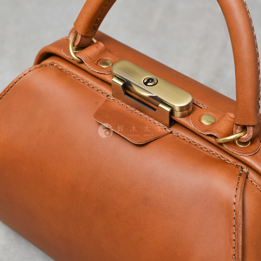 職人手作皮革Organ兩用口金手提包，採用棕褐色皮革，配備古銅色金屬鎖扣和提把。