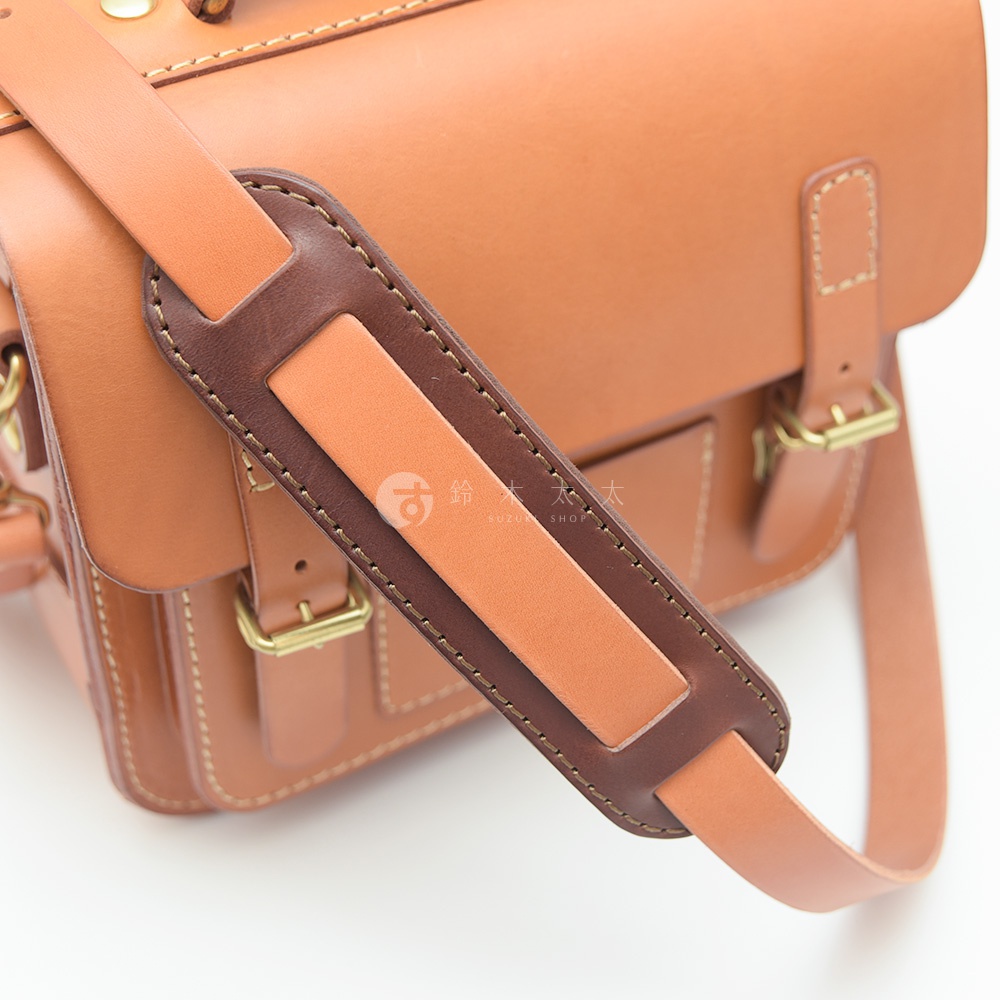 職人手作皮革肩墊，採用棕色皮革製成，雙層設計，中間為淺棕色皮革，外圍為深棕色皮革，邊緣有縫線裝飾，搭配同色系皮革包款。