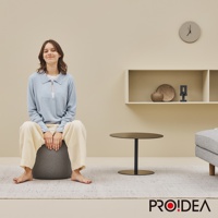 一位年輕女子坐在深灰色針織彈力平衡球迷你款上，此款平衡球採用耐磨針織材質，適合居家收納與運動。