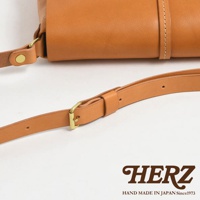 日本HERZ品牌手工製作的淺棕色皮革馬鞍包，特寫其可調節的肩帶和精緻的扣環細節。