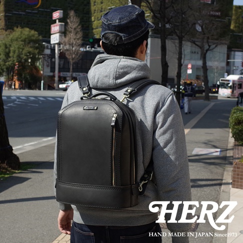 黑色皮革立體商務後背包，具有簡潔的線條設計和金屬拉鍊，背包肩帶可調整。