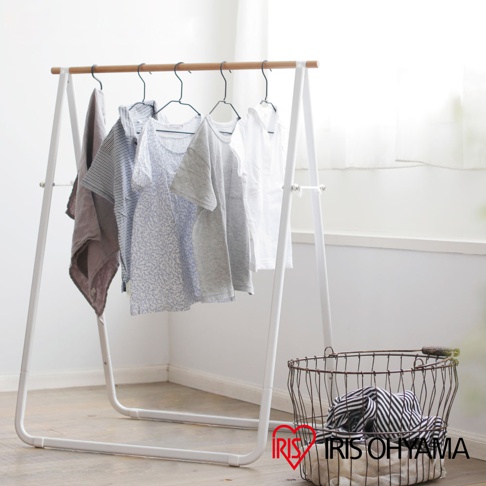 簡約的白色A字形曬衣架，頂部橫桿為原木材質，掛有條紋襯衫、碎花上衣、灰色T恤、白色襯衫及一塊深棕色布料，下方擺放著一個裝有條紋衣物的金屬線籃。