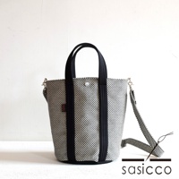 三河木綿刺子織兩用水桶包，棋盤格紋黑白色，搭配黑色織帶提把與可拆卸斜背帶，包身結構挺立。