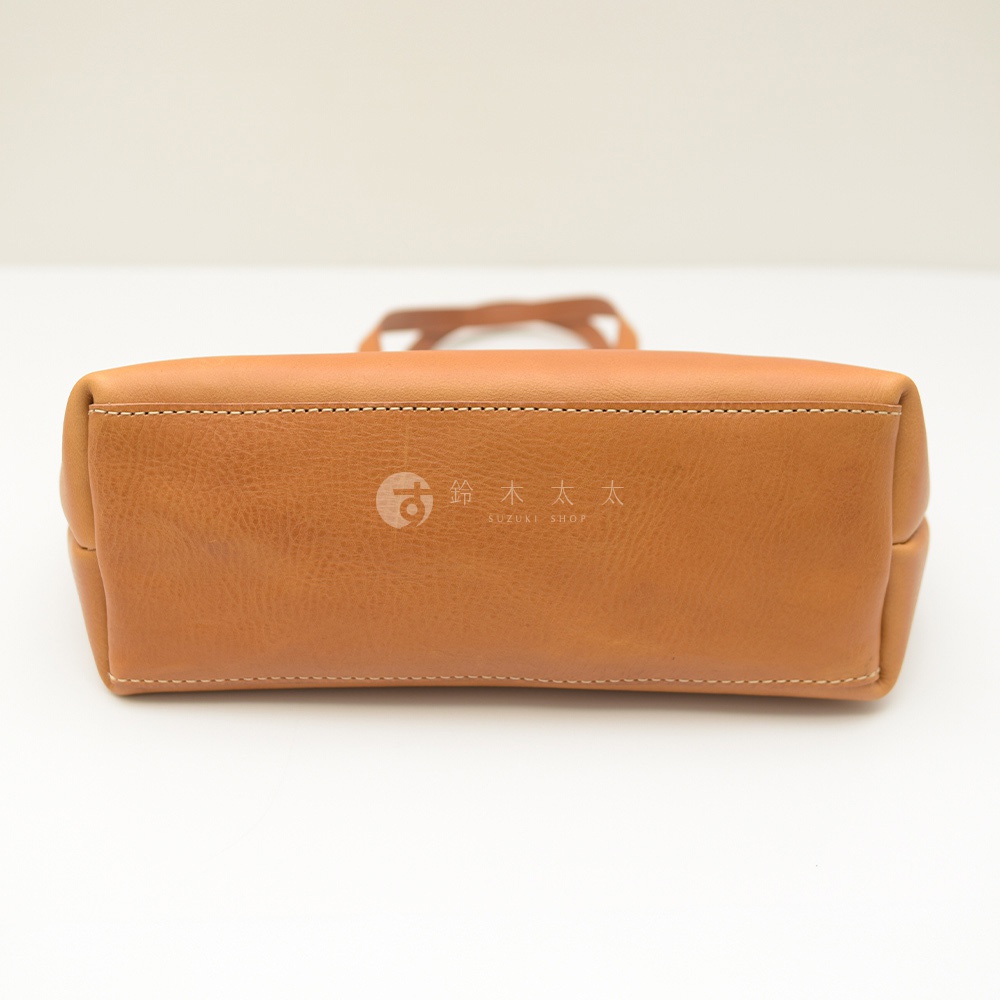 職人手作皮革4口袋極簡托特包 T-3，展示包款底部，採用淺棕色皮革，車縫白色縫線，中央壓印有「鈴木太太 SUZUKI SHOP」品牌標誌。