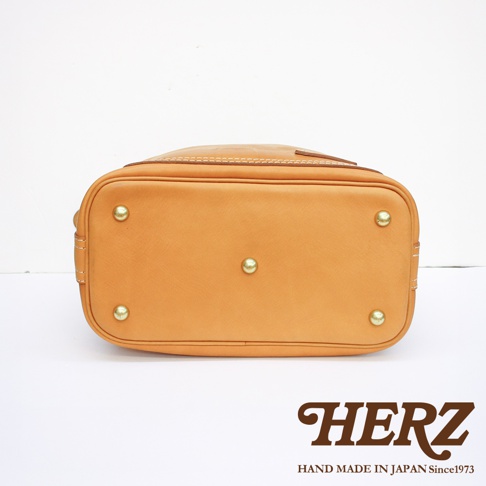 職人手作皮革厚實單肩波士頓包底部，設有五個黃銅腳釘，皮革呈現自然焦糖色，車縫線清晰。