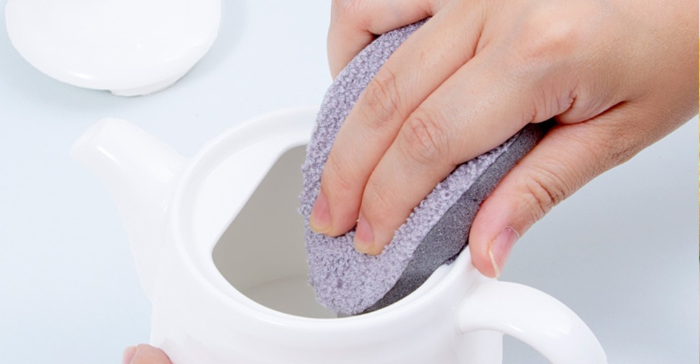 手拿灰色菜瓜布清潔白色茶壺內部