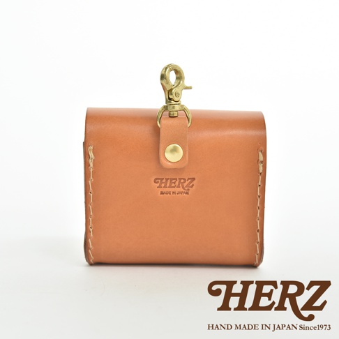 職人手作皮革耳機收納包，採用鞣製皮革製作，附有黃銅色金屬扣環與按鈕，正面壓印有「HERZ」品牌標誌及「MADE IN JAPAN」字樣，手工縫線清晰可見。