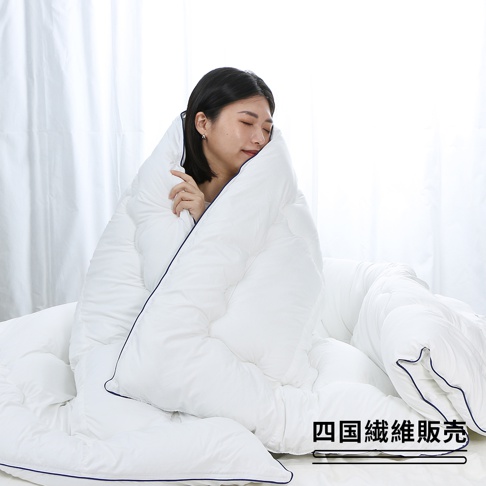 一名女子被白色輕棉雙人SOFAIR無重力空氣被包裹，被子蓬鬆柔軟，邊緣有深藍色滾邊。