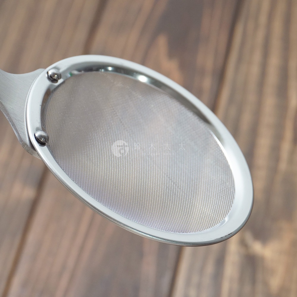 不鏽鋼製成的萬用撈泡勺，勺頭為橢圓形網篩設計，細密的網孔清晰可見，勺柄與勺頭連接處有兩個鉚釘固定。