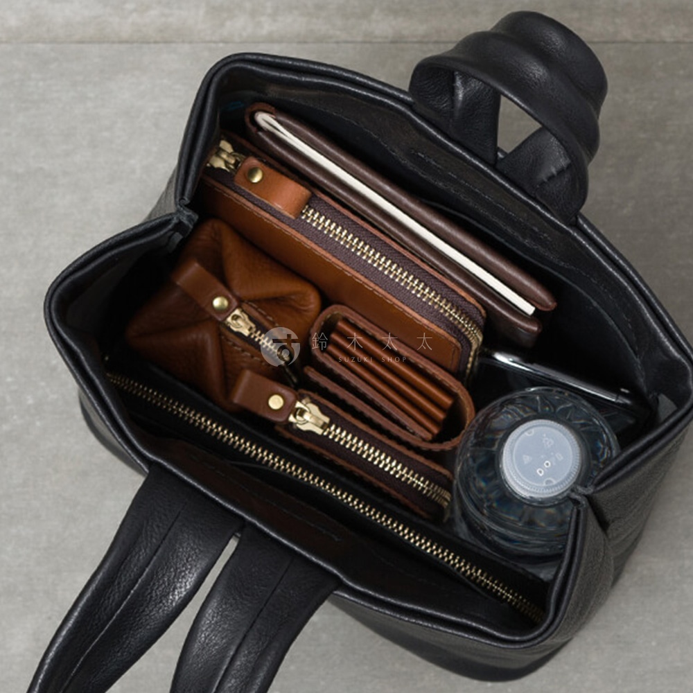 黑色皮革單柄手提包，內部裝有棕色皮革錢包、零錢包和筆記本，以及一瓶水。