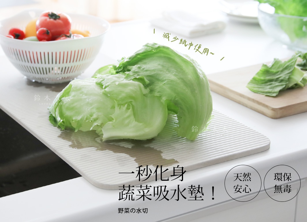 寬版珪藻土吸水墊，表面有細緻的條紋，淺米色。墊上放著兩顆新鮮的結球萵苣，葉片翠綠，部分葉片帶有水珠。背景還有一個白色的濾水盆，盆裡有番茄、小黃瓜等蔬菜。