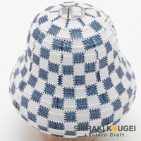 白色紙質提燈，表面印有藍色棋盤格紋飾，頂部有金屬支架，底部為木製底座。