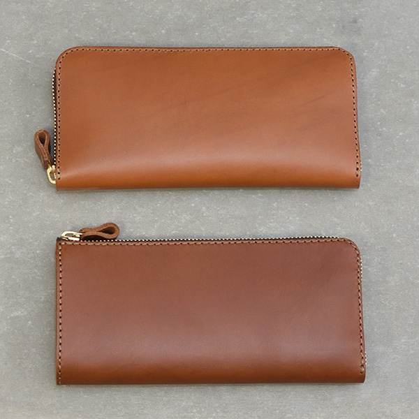 兩款棕色皮革製的L型長夾，上方長夾為較寬的款式，下方為較窄的款式，兩款皆有金色拉鍊及同色系皮革拉環。