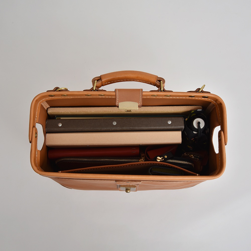 棕色皮革製成的公事包，頂部有提把和金屬扣環，包內裝有文件夾、筆記本、錢包和摺疊傘。